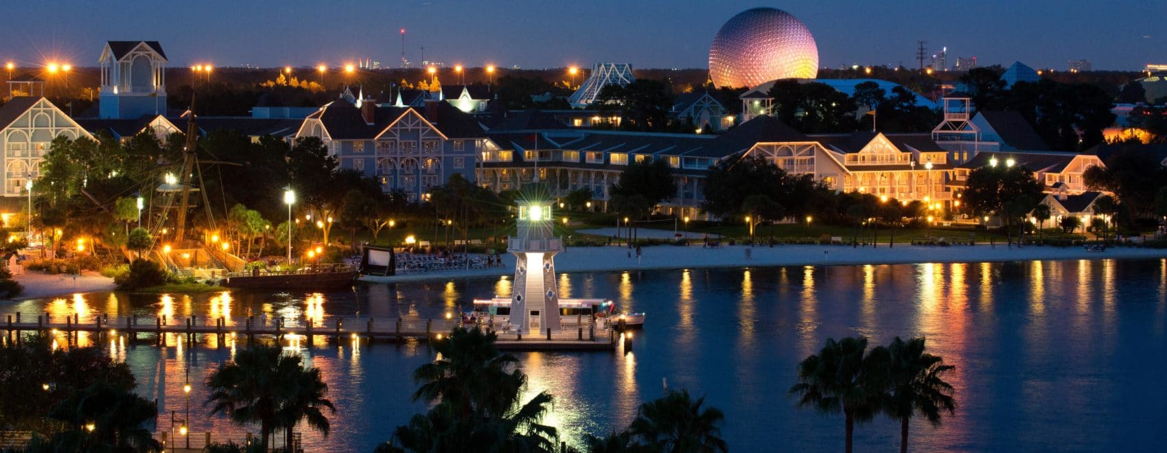Walt Disney World's beautiful Beach Club resort lit up at night, with Epcot visible in the background