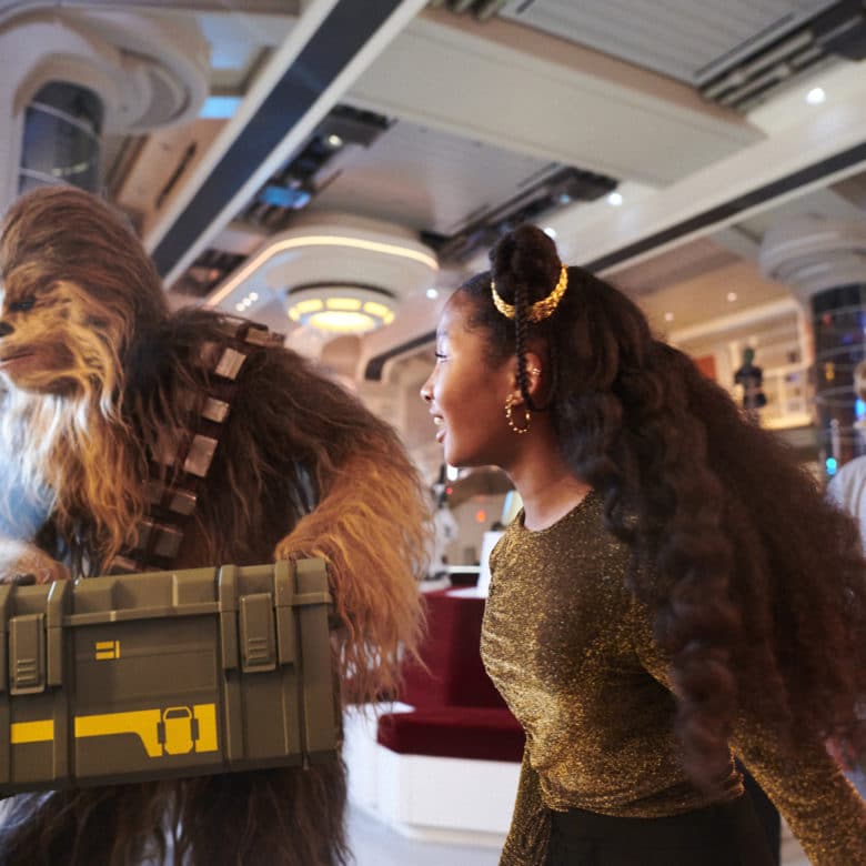 Chewie and some visiting guests carries a secret mission crate through the lobby of the Star Wars Galactic Starcruiser, Halcyon