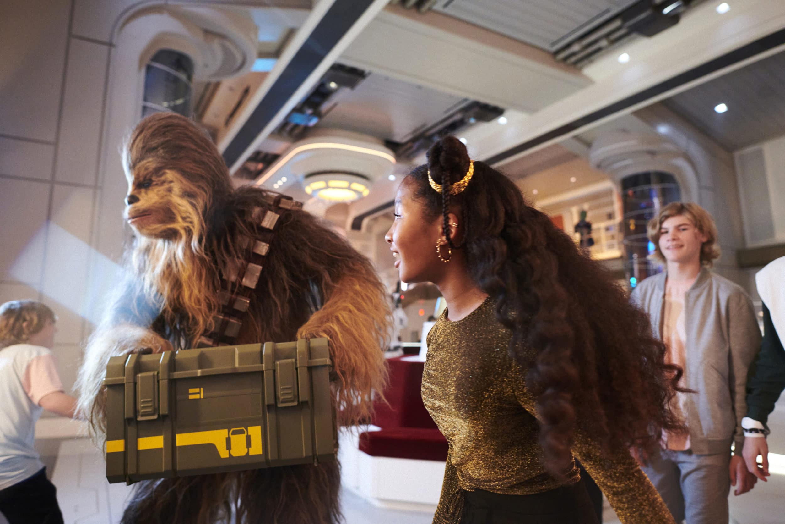Chewie and some visiting guests carries a secret mission crate through the lobby of the Star Wars Galactic Starcruiser, Halcyon