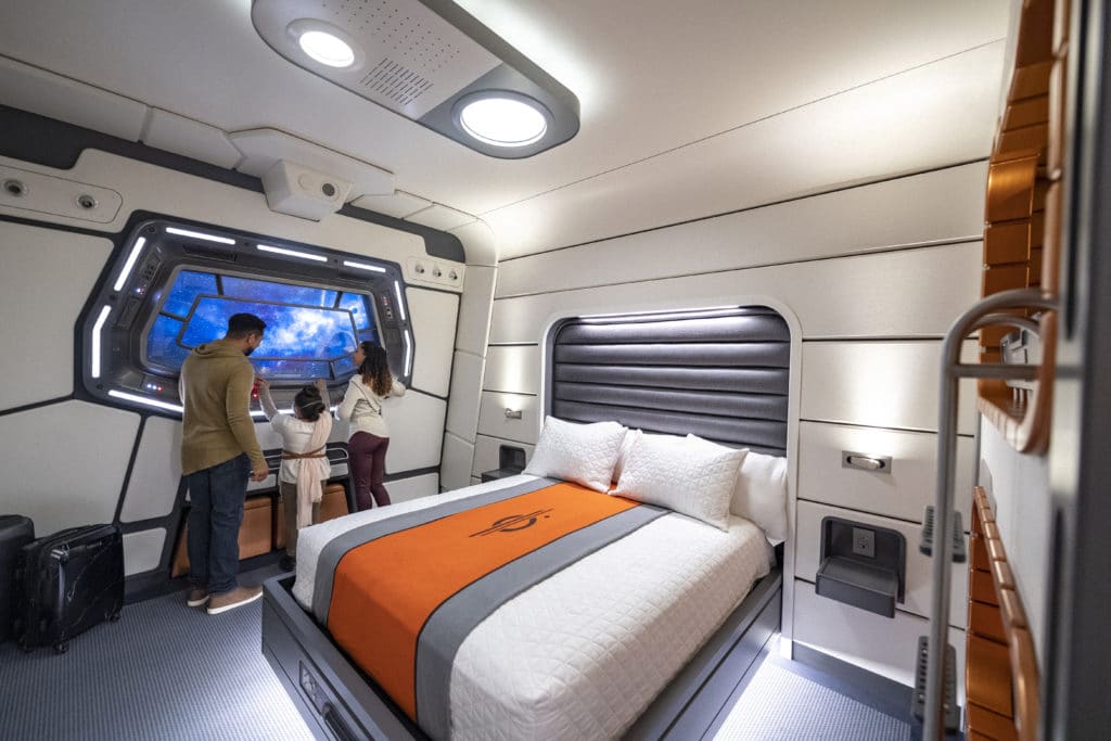 A family with a young kid enjoys the incredible space views out their cabin window in the amazing new Disney Star Wars hotel, the Galactic Starcruiser