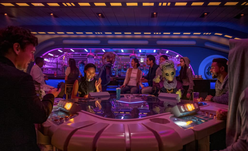 Guests and costumed character aliens enjoy vacation and cool cocktails together in the Star Wars Galactic Starcruiser, Halcyon's ultra-awesome Sunlight Loung