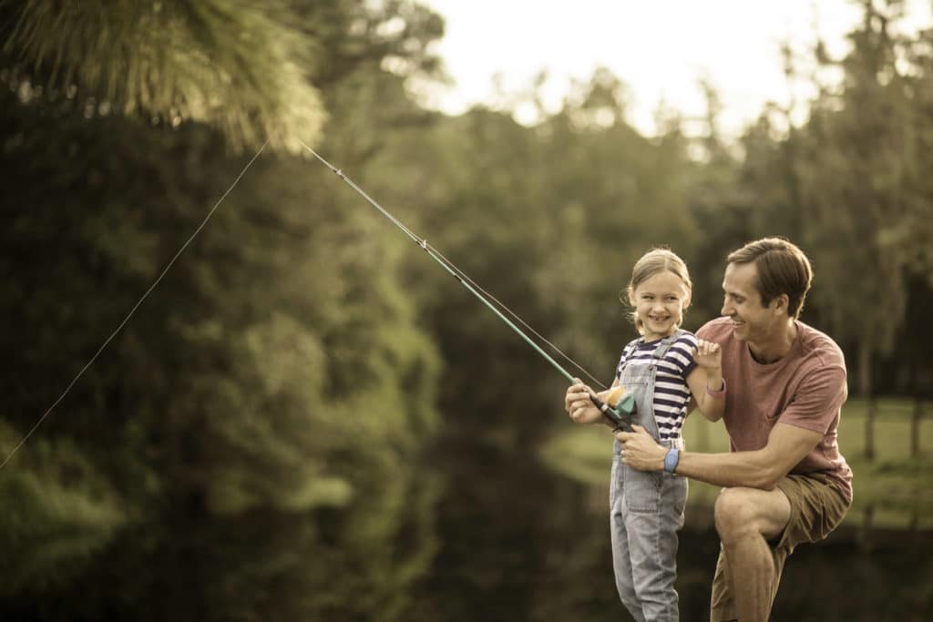 A happy father teaches his delighted daughter to fish at one of the multitude of activities offered at the Fort Wilderness Resort in Walt Disney World