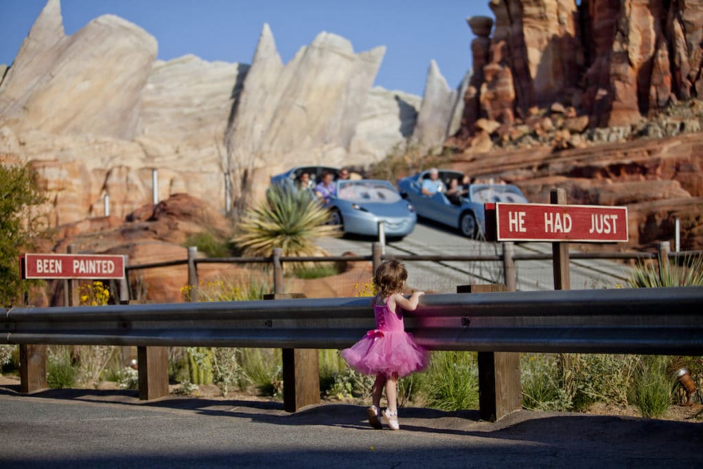 Everyone's enjoying a wonderful trip to the Disneyland Resort as a young girl in a pink tutu dress watches the lively racing blue cars swerve through the canyons of Radiator Springs, racing to the finish of this fan favorite Cars Land attraction.