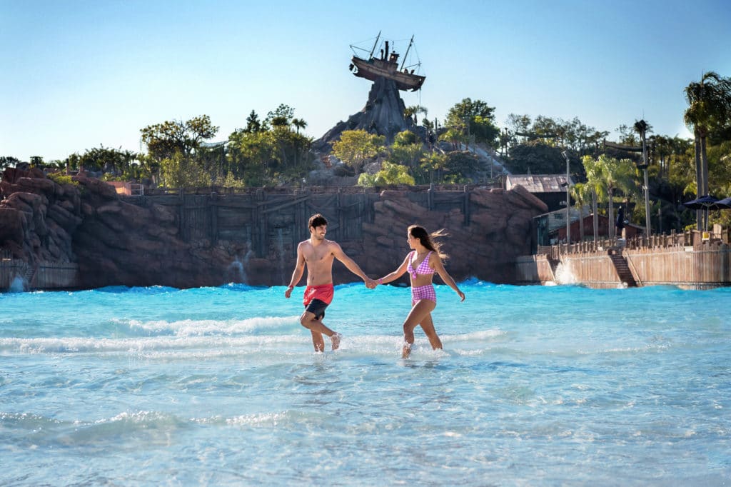 A bright-swimsuit-clad man and woman splash through Walt Disney World's Typhoon Lagoon on a sunny Florida day during their romantic honeymoon at Disney World