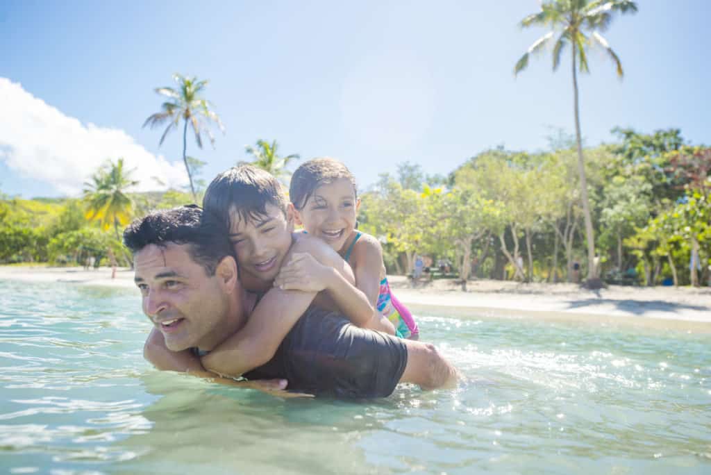 Brother and sister catch a ride on Dad's back while enjoying the Castaway Cay beaches on their Disney Cruise Line special event vacation