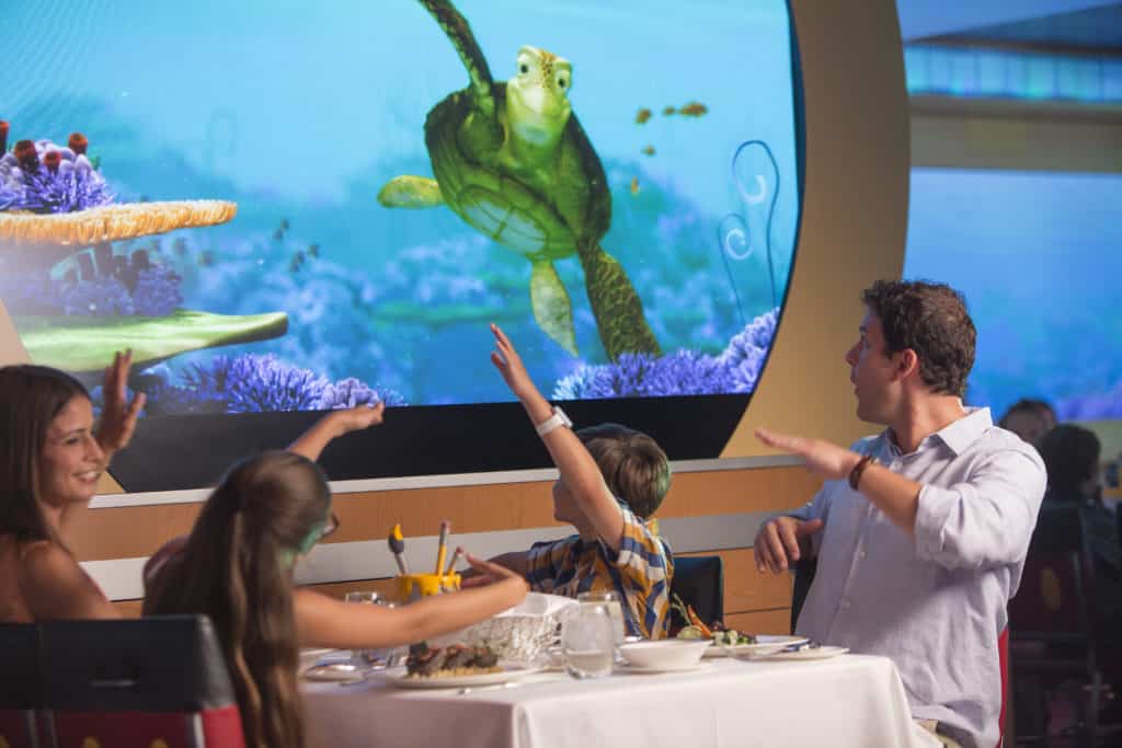 A young family with two happy kids enjoys snacking "under the sea" with their Disney Cruise special event of Pixar Day at sea
