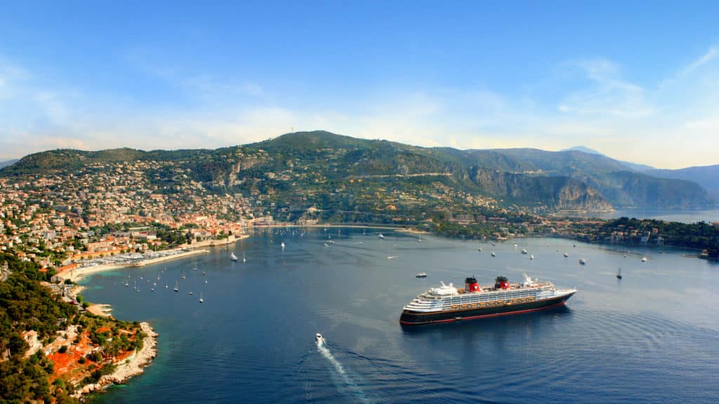 One of the gorgeous Disney ships of the Disney Cruise Line, Disney Magic, rests safely in a gorgeous Mediterranean cove.