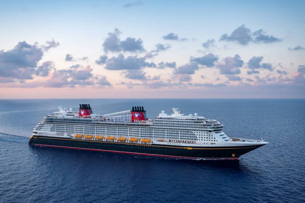 The newest of the Disney ships in the Disney Cruise Line fleet is the beautiful Disney Wish pictured here in the open ocean under a stunning sunset