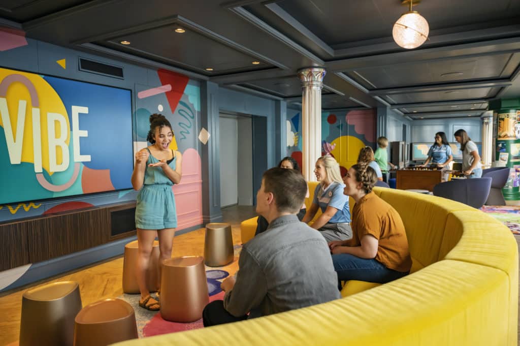 Disney ships provide fun for all ages with many different youth clubs onboard - like this teen club "Vibe" where this group of teens is happily playing charades and relaxing without their parents